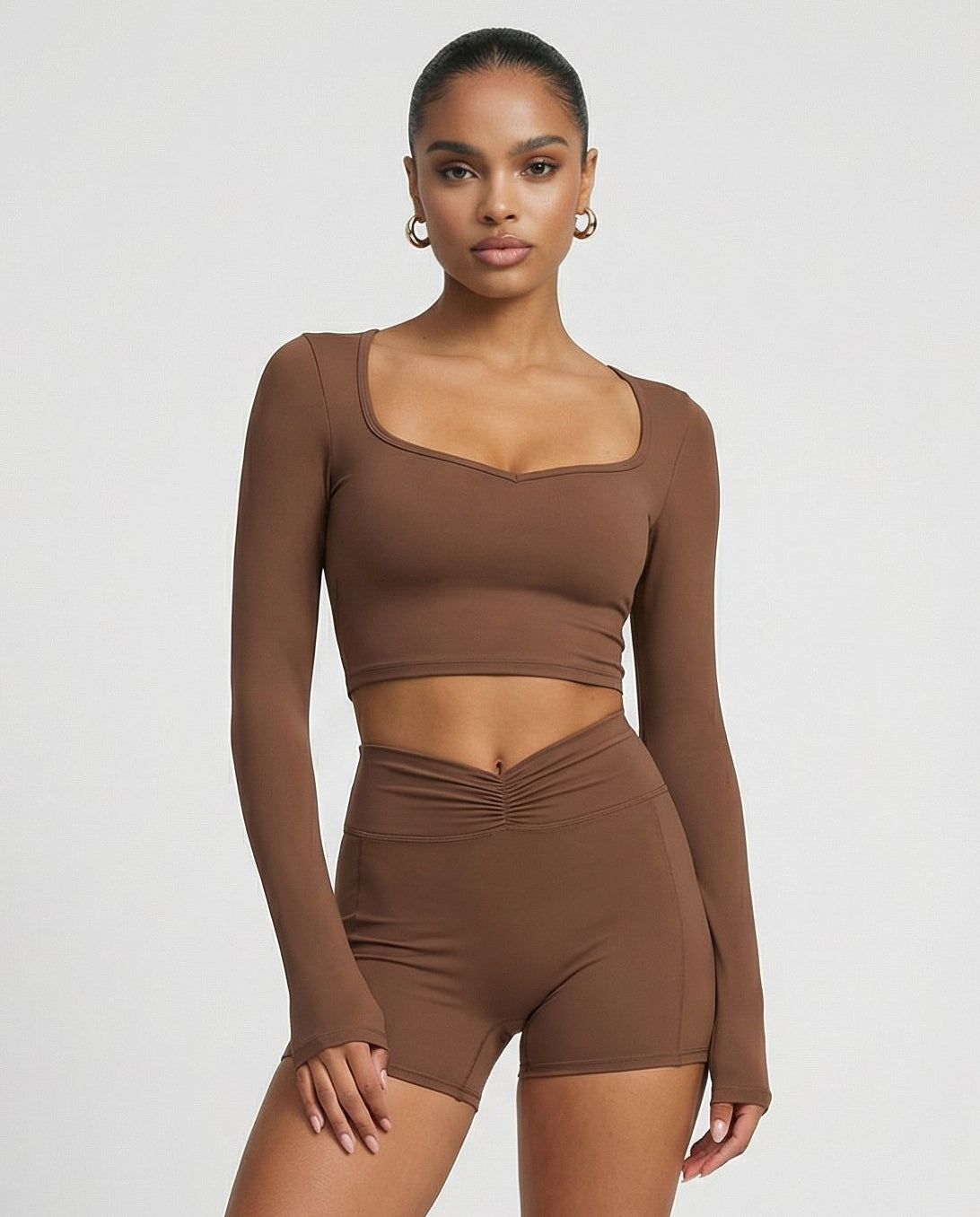 Seen women's activewear set with brown sculpting biker shorts and long sleeve top, front view showcasing fitted athletic design.
