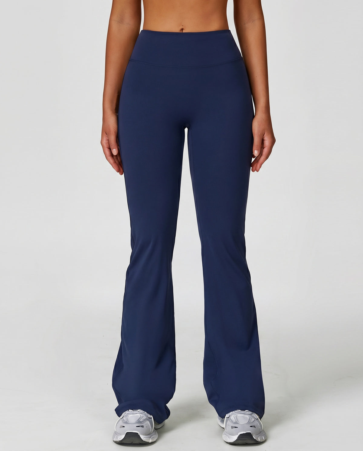 Front view of navy flare high waist sculpting yoga leggings with a smooth compression waistband and sweeping flare leg, paired with grey sneakers.