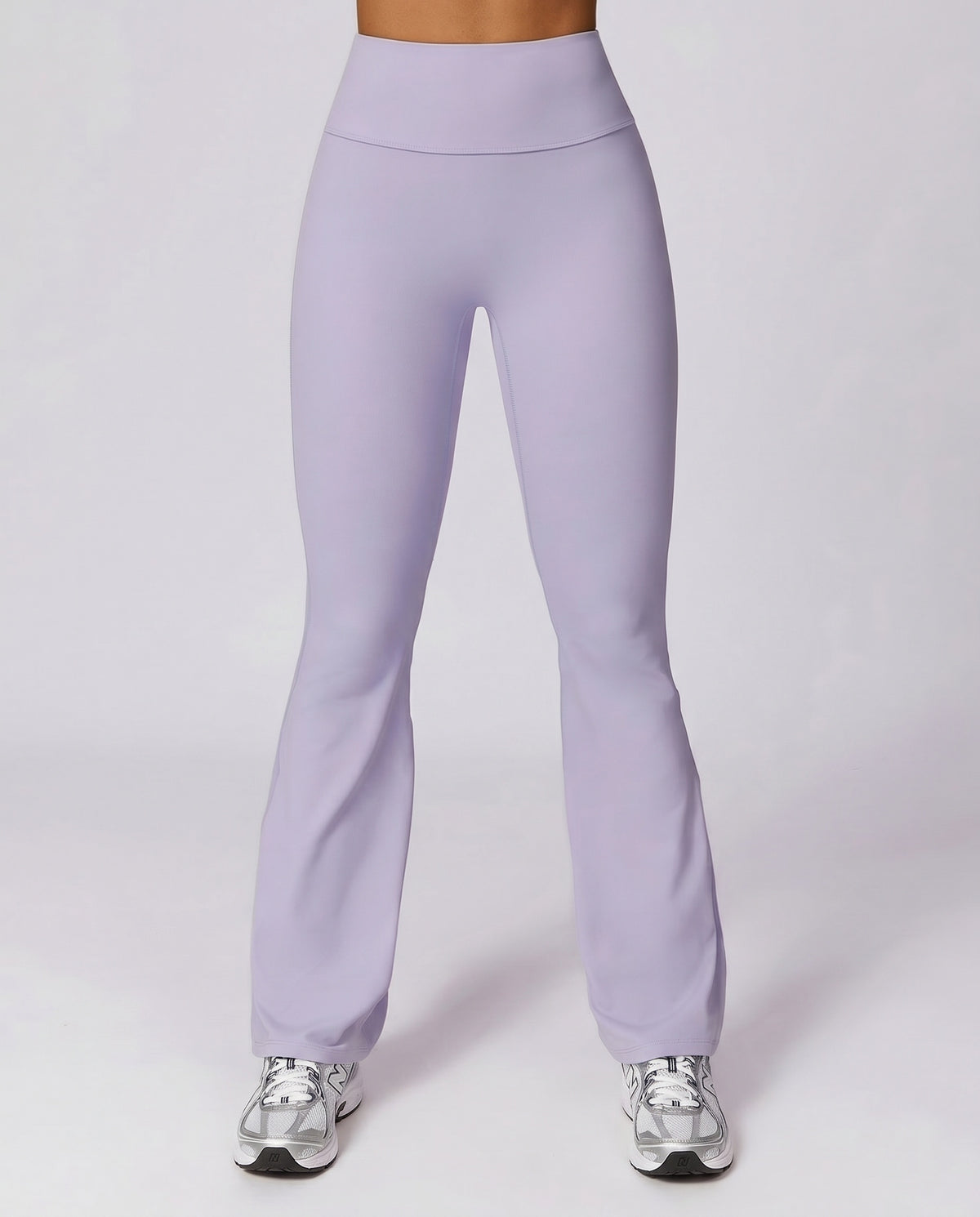 Front view of flare high waist sculpt yoga leggings in lavender purple, featuring a wide sculpting waistband and full-length flare leg, paired with silver sneakers.