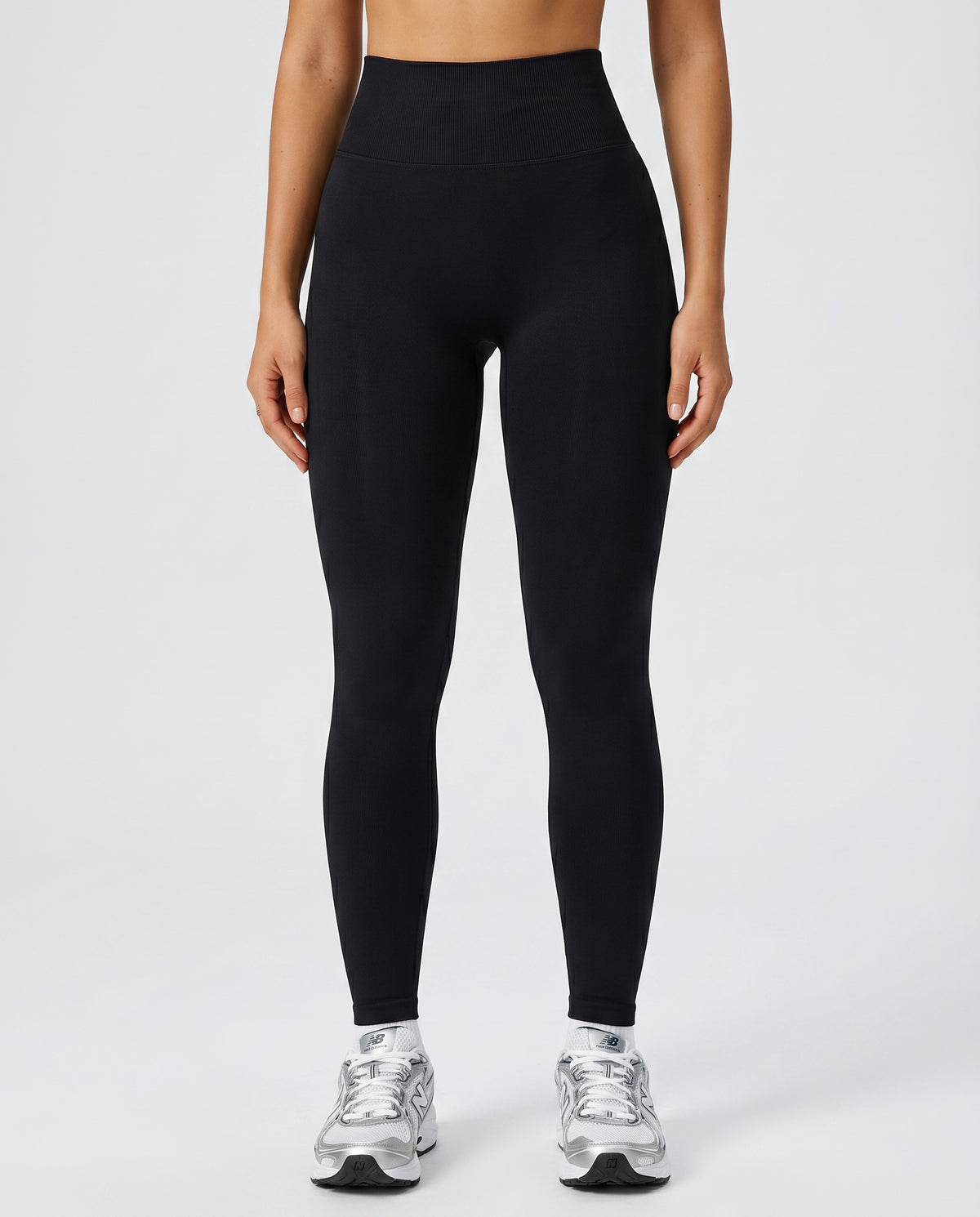 Front view of seamless high waist sculpting compression leggings in black, showing ribbed waistband and full-length squat-proof fit paired with white sneakers.