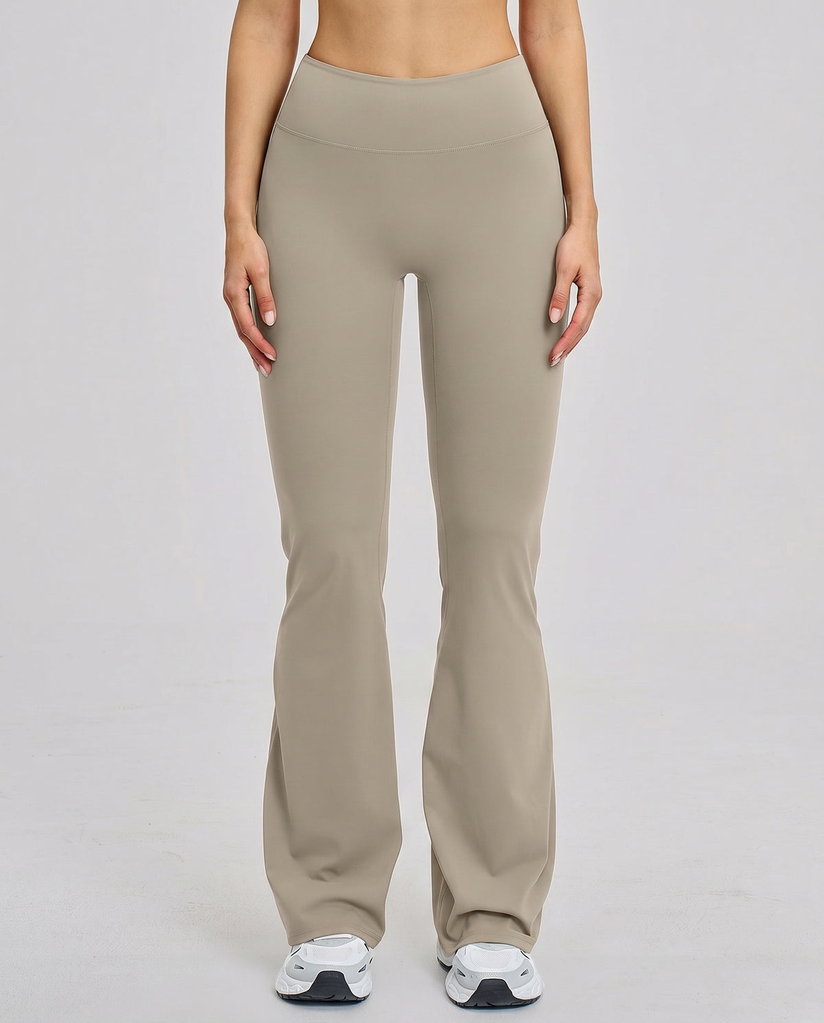 Front view of flare high waist sculpt yoga leggings in mocha featuring a wide waistband and lengthening flare leg silhouette paired with white sneakers.