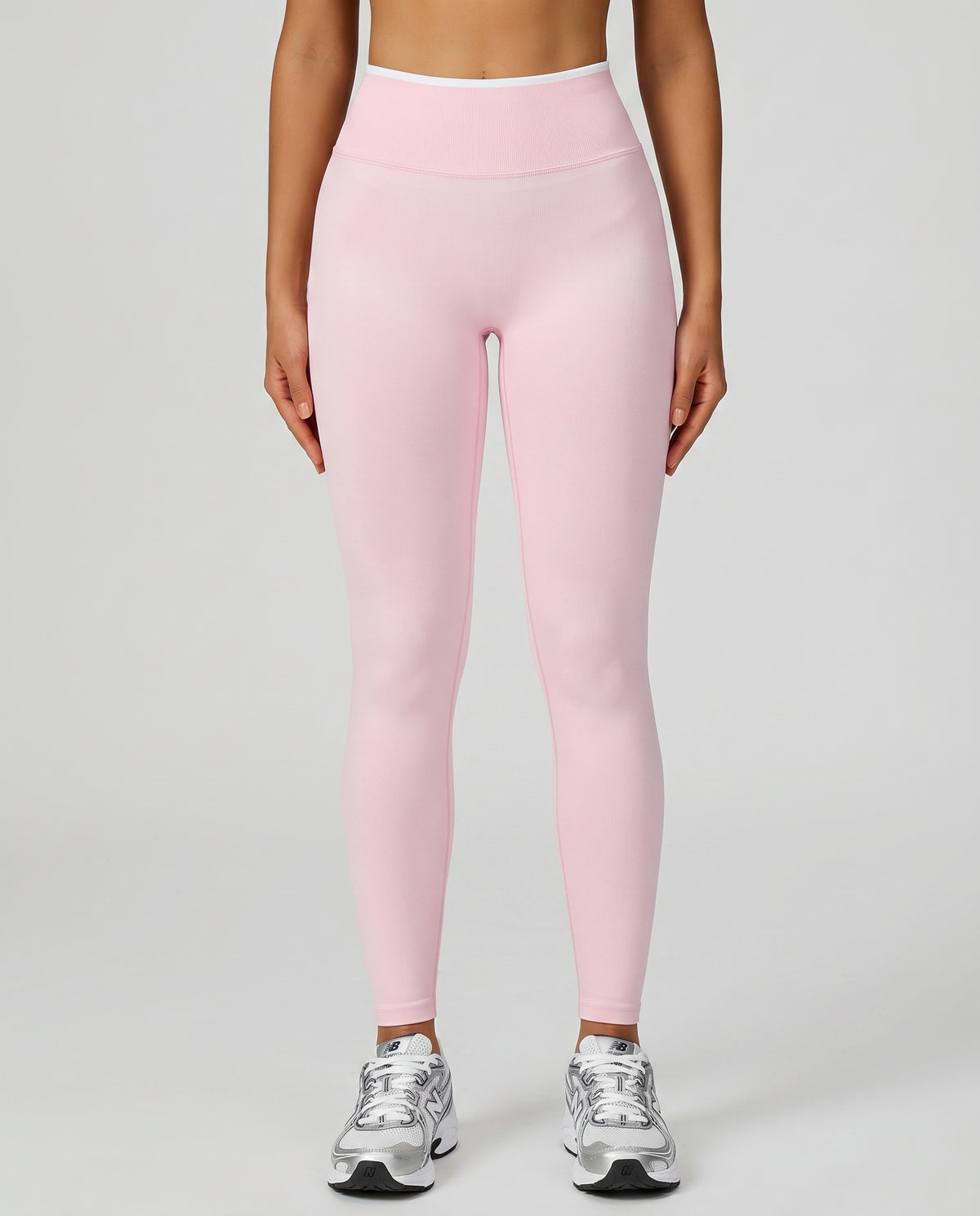 Front view of seamless high waist sculpting compression leggings in pink, showing smooth no-front-seam silhouette paired with silver New Balance sneakers.