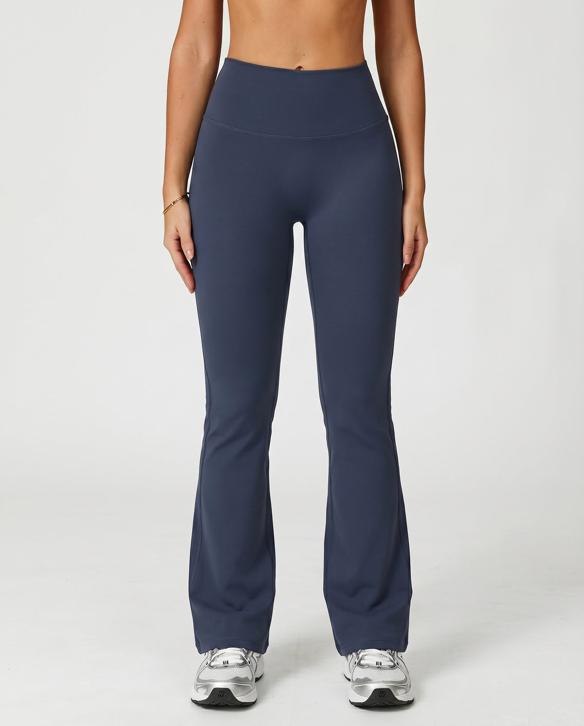 Front view of flare high waist sculpt yoga leggings in navy featuring a wide compression waistband and full-length flare leg silhouette paired with white sneakers.
