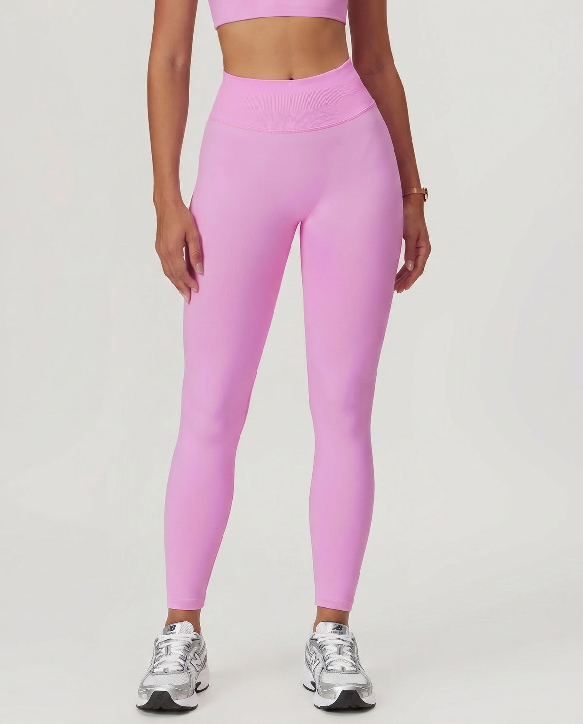 Front view of seamless high waist sculpting compression leggings in pink, showing full-length fit with ribbed waistband and ankle-length silhouette paired with sneakers.