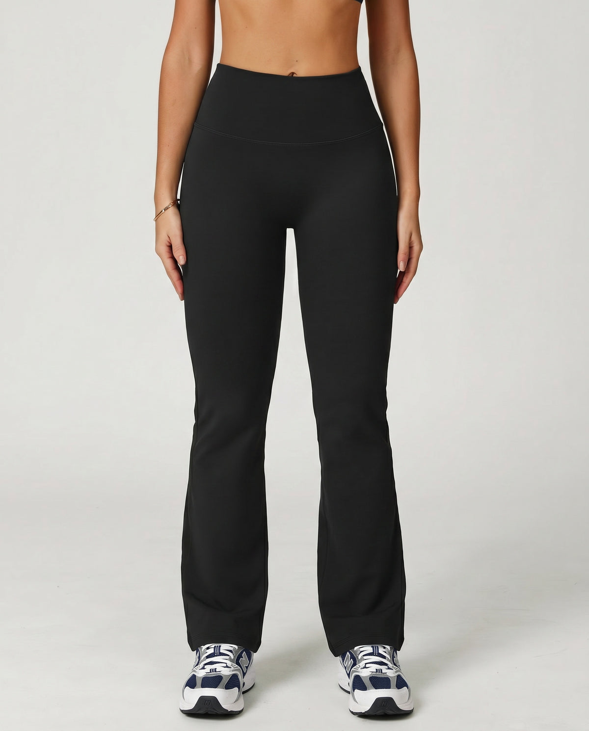 Front view of black flare high waist sculpting yoga leggings with a smooth compression fit and lengthening flare leg silhouette, paired with sneakers.
