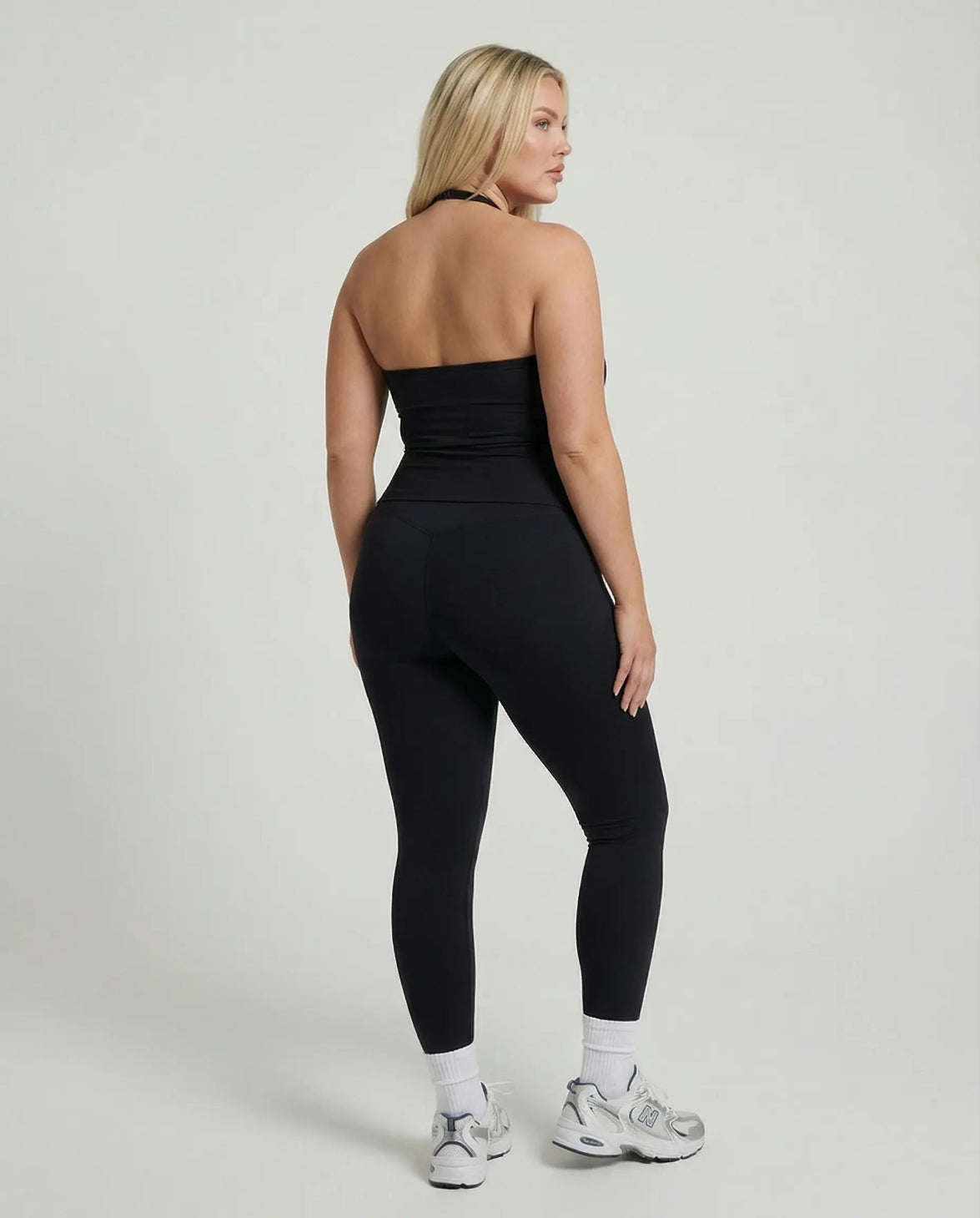 Model wearing a black seamless halter sculpt leggings set with high waist fitted leggings and athletic sneakers.