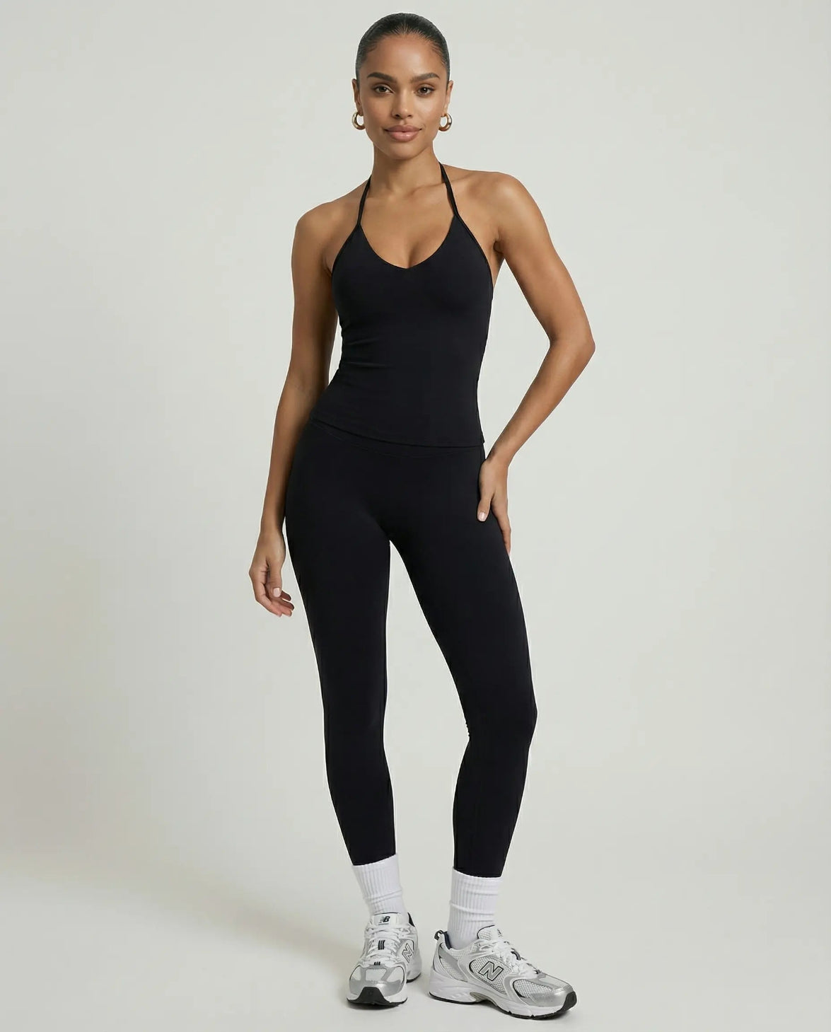 Model wearing a black seamless halter sculpt leggings set with high waist fitted leggings and athletic sneakers.