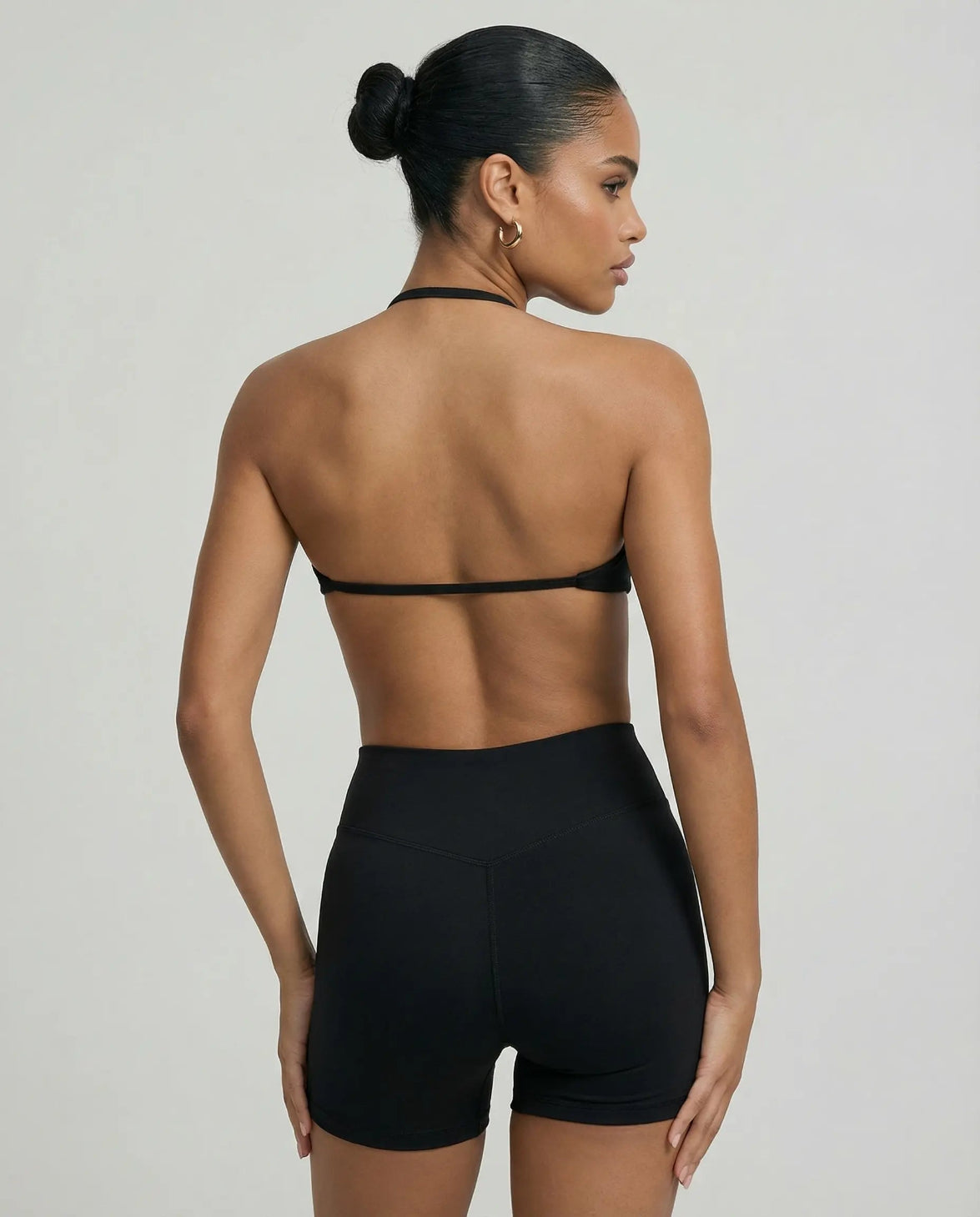 Model wearing a black seamless sculpt gym set with high waist shorts and a supportive sports bra paired with athletic sneakers.