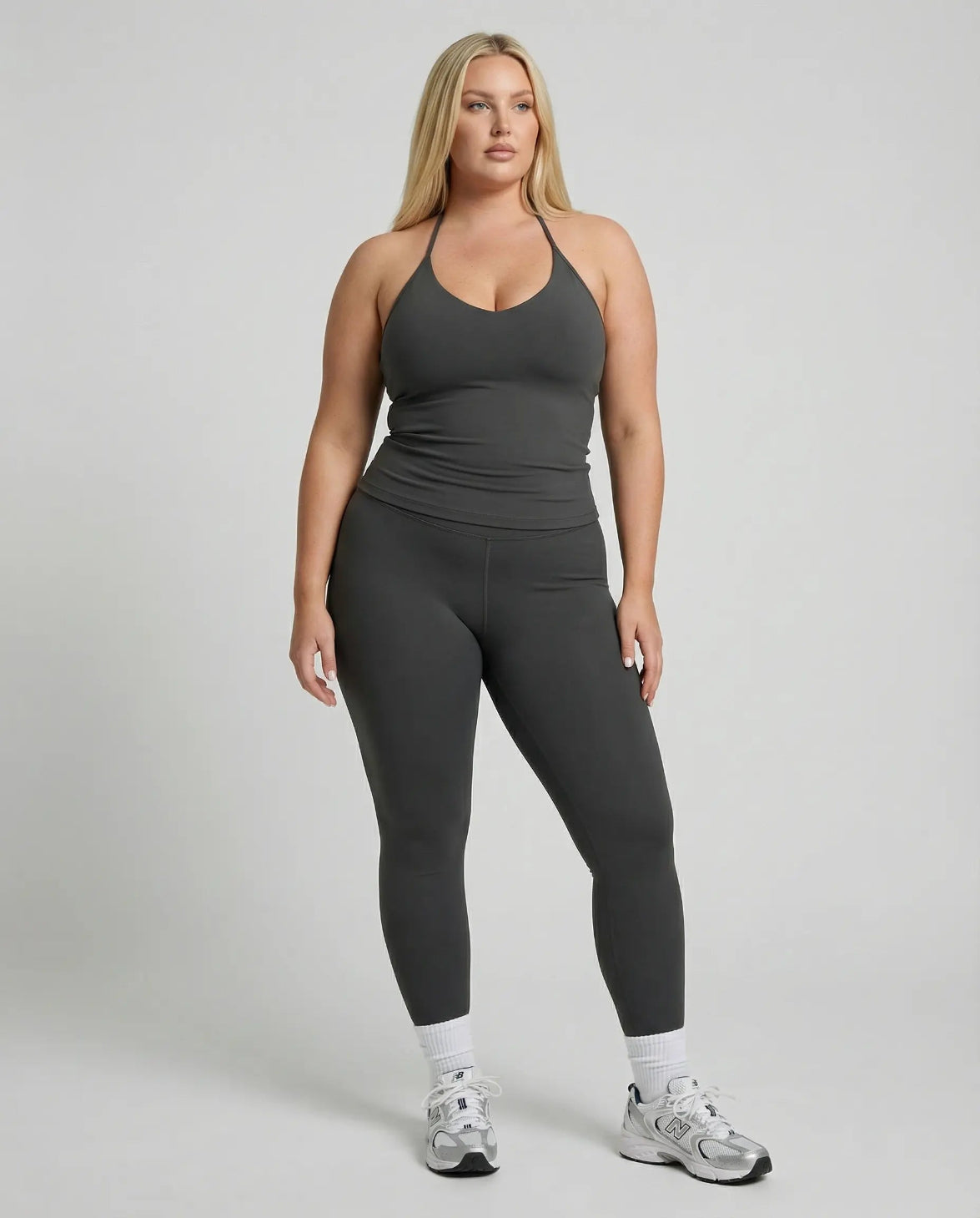 Model wearing a gray seamless halter sculpt leggings set with high waist fitted leggings and athletic sneakers.