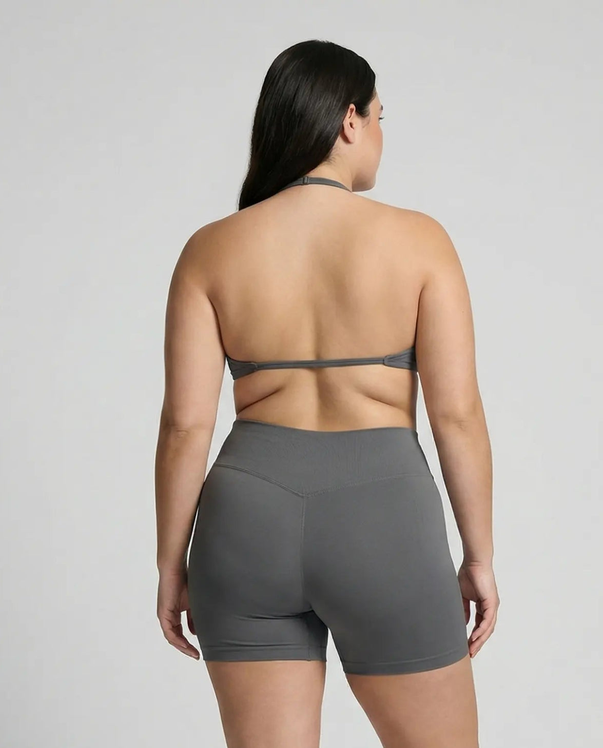 Model wearing a grey seamless sculpt gym set with high waist shorts and a supportive sports bra paired with athletic sneakers.