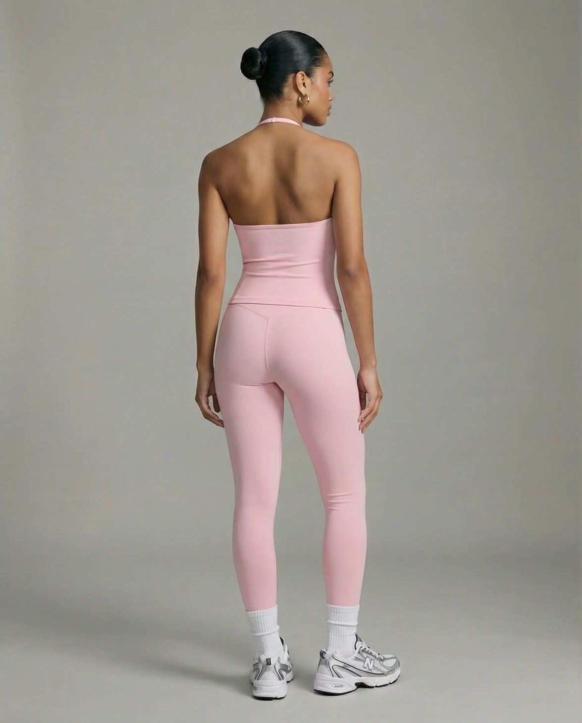 Model wearing a pink seamless halter sculpt leggings set with high waist fitted leggings and athletic sneakers.