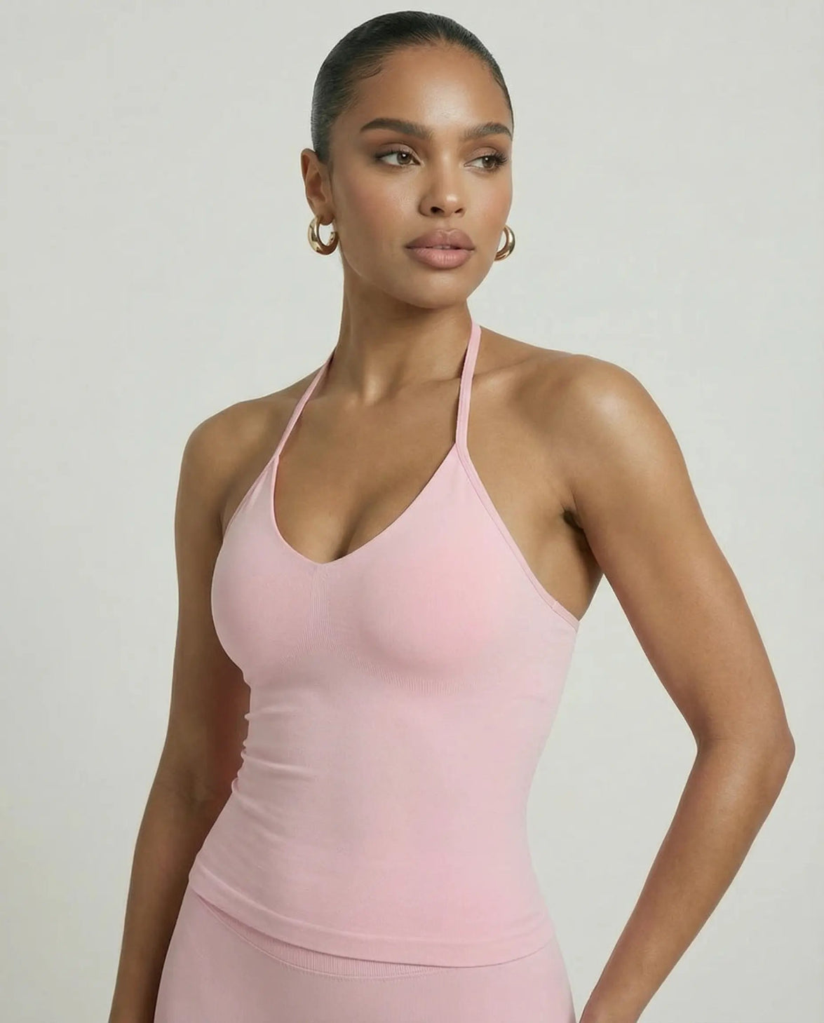 Model wearing a pink seamless halter sculpt leggings set with high waist fitted leggings and athletic sneakers.