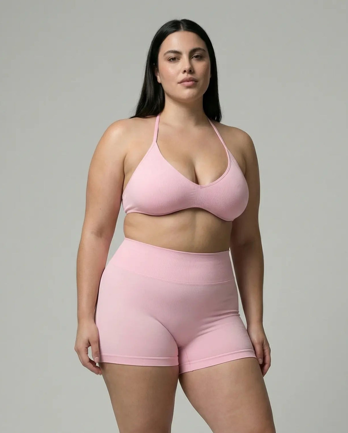 Model wearing a pink seamless sculpt gym set with high waist shorts and a supportive sports bra paired with athletic sneakers.