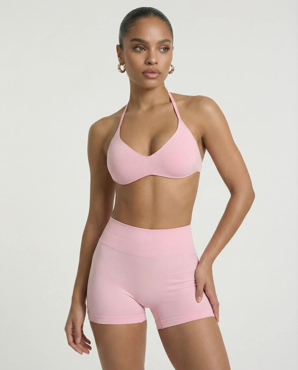 Model wearing a pink seamless sculpt gym set with high waist shorts and a supportive sports bra paired with athletic sneakers.