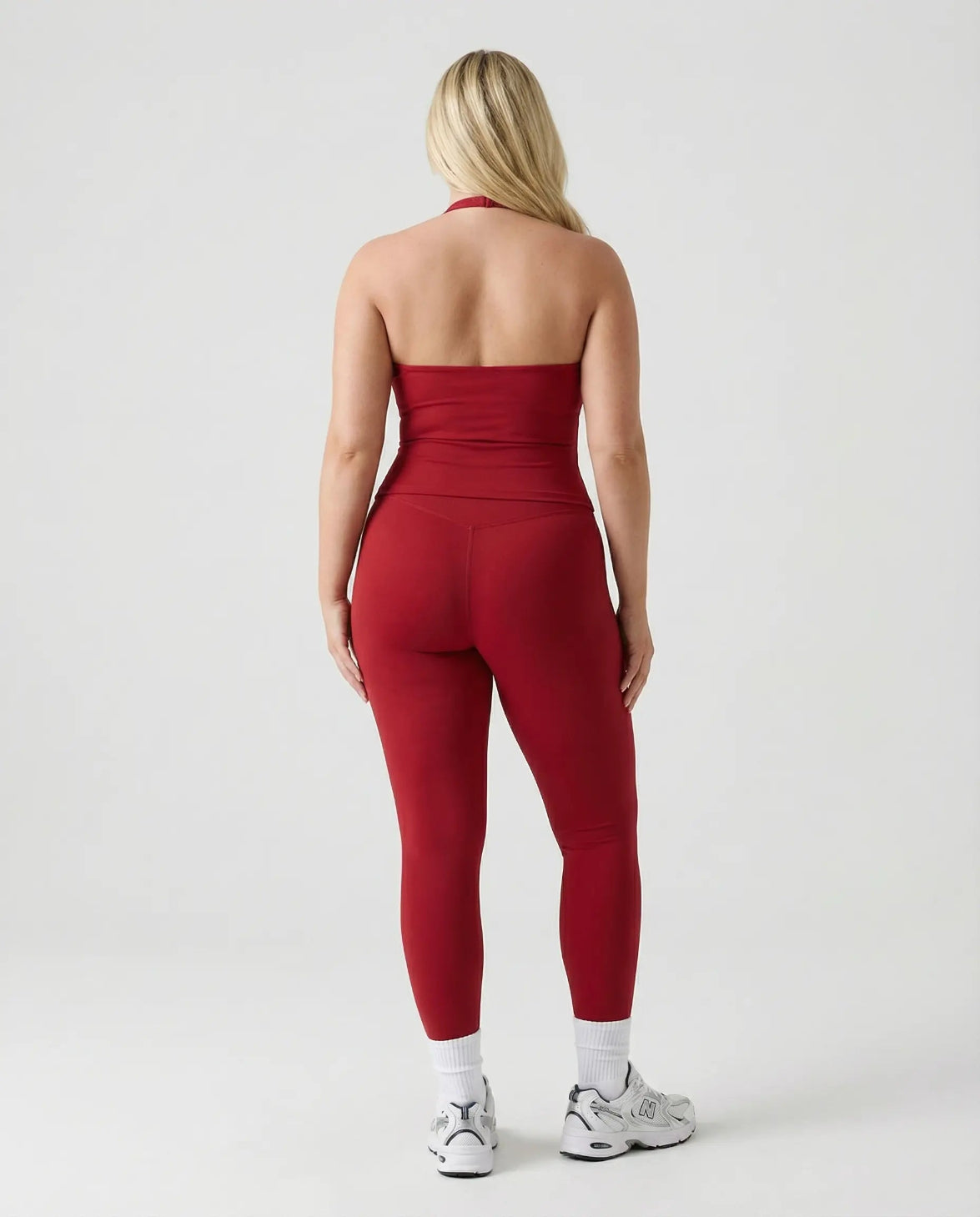 Model wearing a red seamless halter sculpt leggings set with high waist fitted leggings and athletic sneakers.