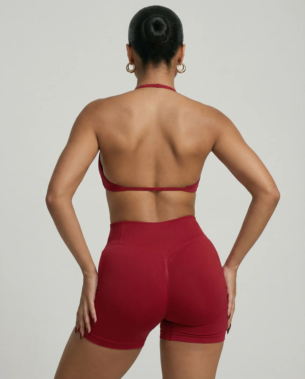 Model wearing a red seamless sculpt gym set with high waist shorts and a supportive sports bra paired with athletic sneakers.