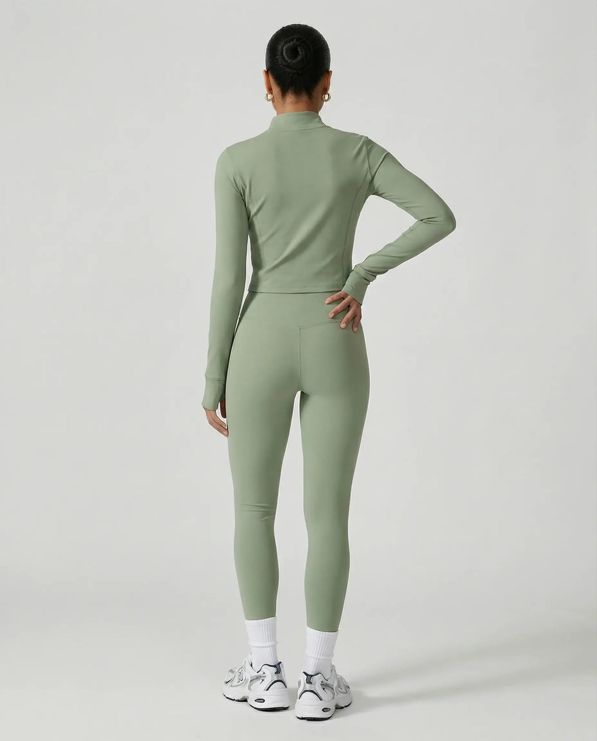 Woman wearing a seamless sculpting three piece activewear set with high waist leggings, sports bra, and fitted jacket paired with sneakers.