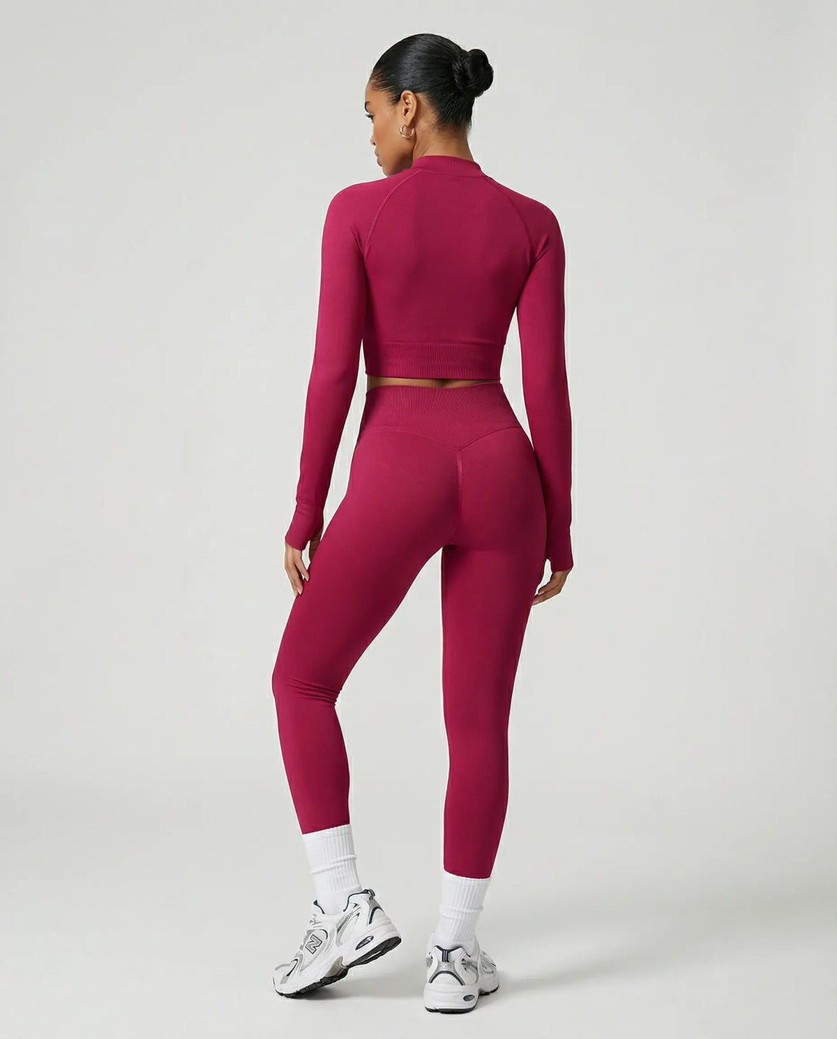 Woman wearing a seamless sculpting three piece activewear set with high waist leggings, sports bra, and fitted jacket paired with sneakers.