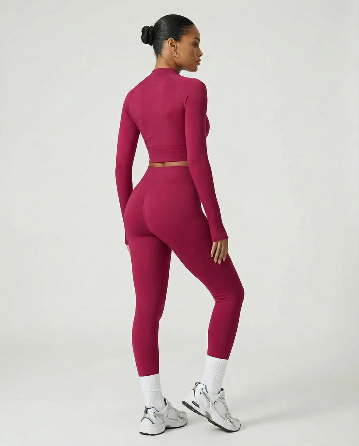 Woman wearing a seamless sculpting three piece activewear set with high waist leggings, sports bra, and fitted jacket paired with sneakers.