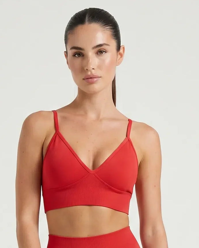 Ghost mannequin front view of red seamless ribbed V-neck bra top showing sculpting neckline and thin straps.