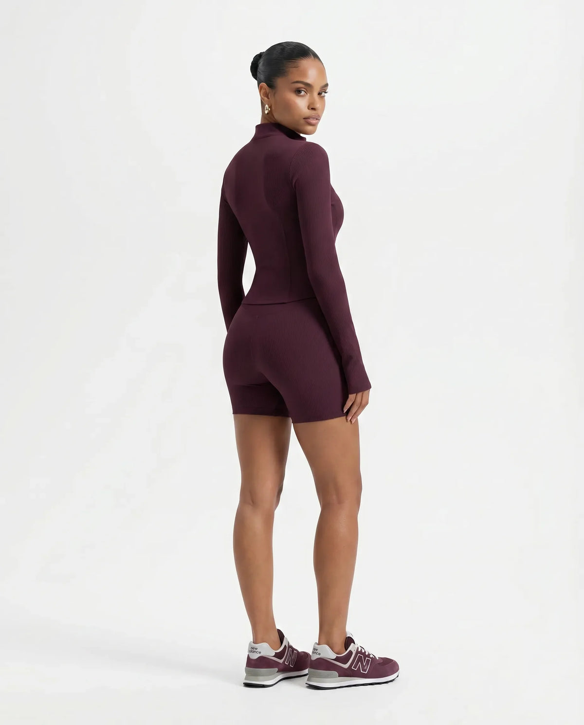 Back view of wine red sculpting zip-up jacket top on ghost mannequin displaying clean back panelling and long sleeves.