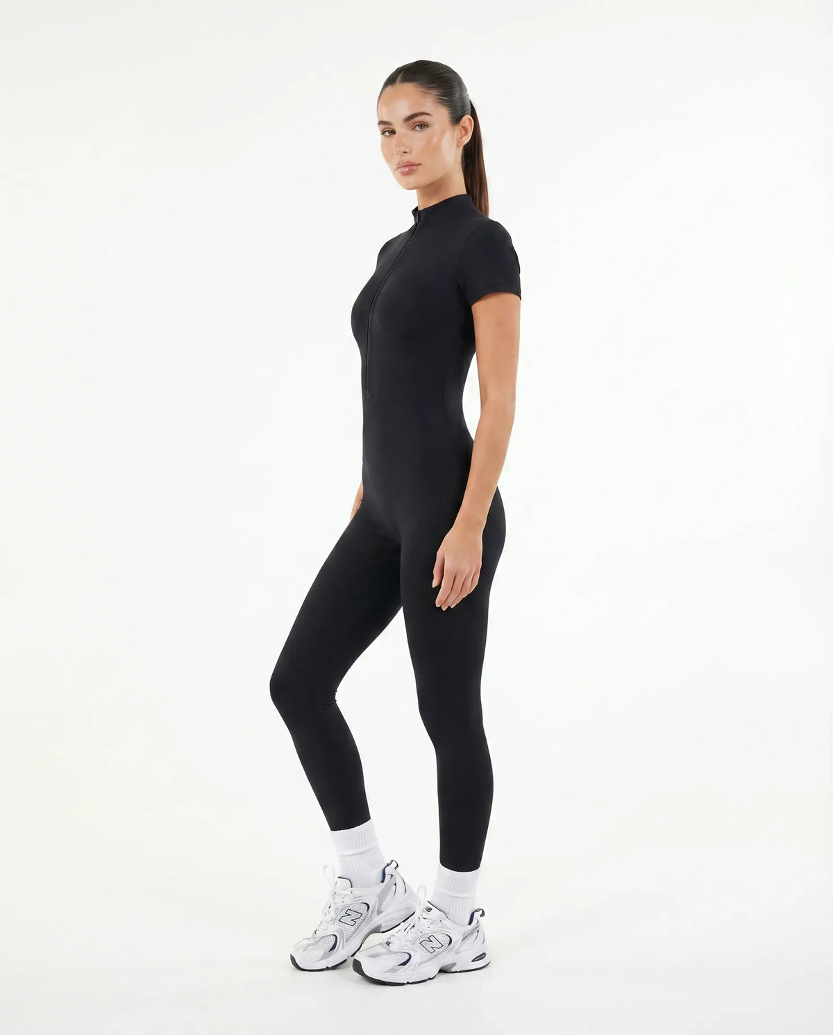 Woman wearing brown jumpsuit legging walking outdoors in natural light with white sneakers and relaxed styling.