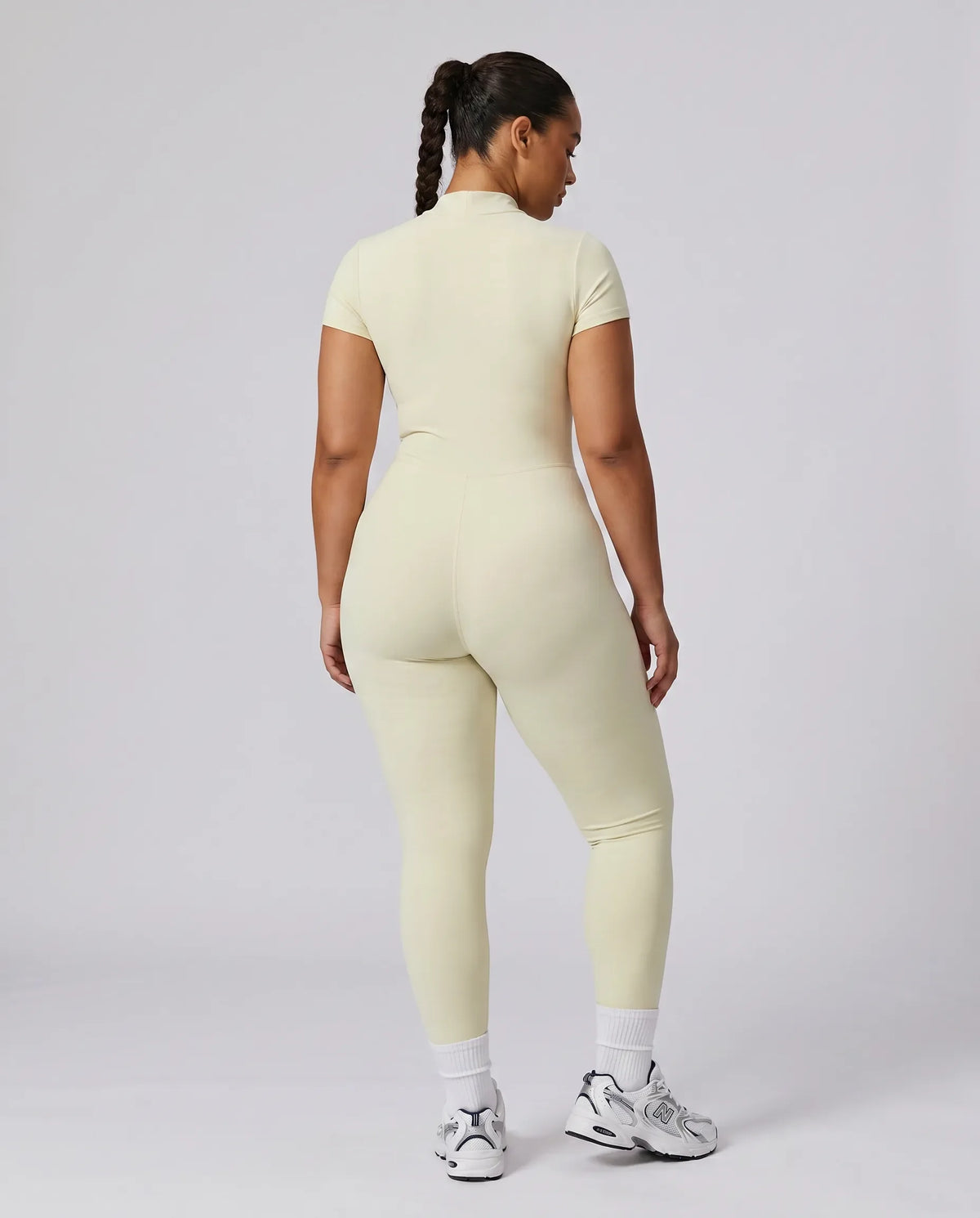 Model facing away in studio showing the back fit of the yellow sculpting activewear jumpsuit.