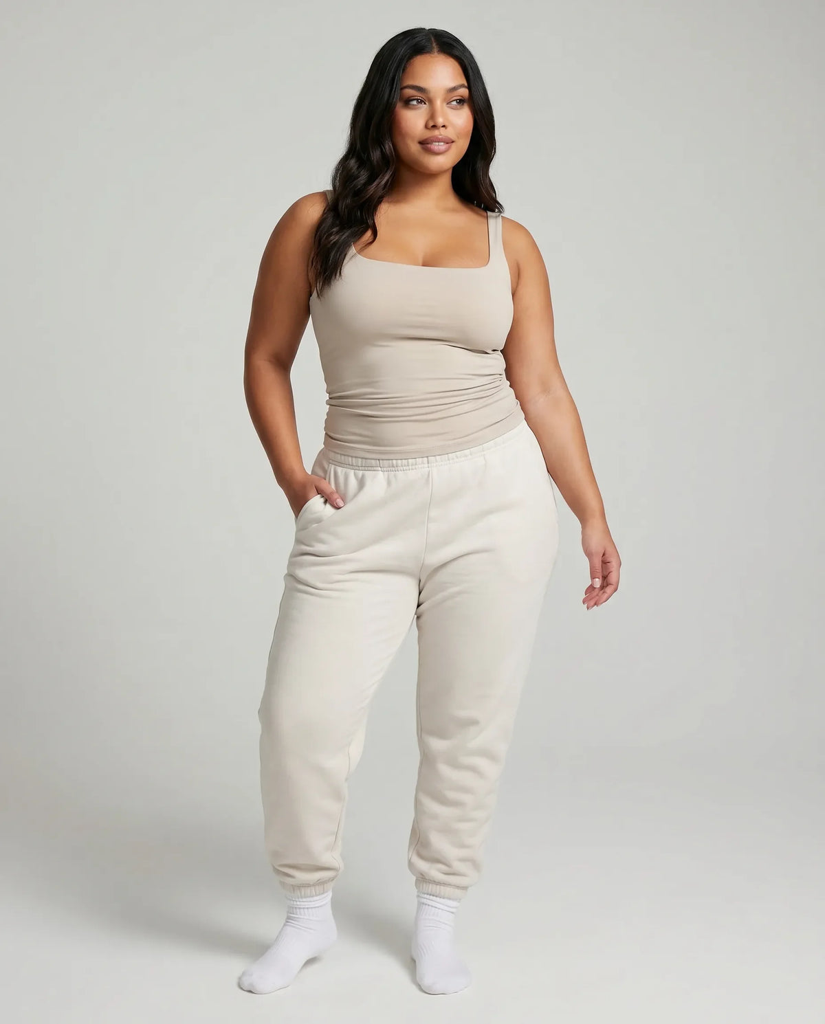 Model wearing beige square neck sleeveless tank top, front studio shot with neutral background.