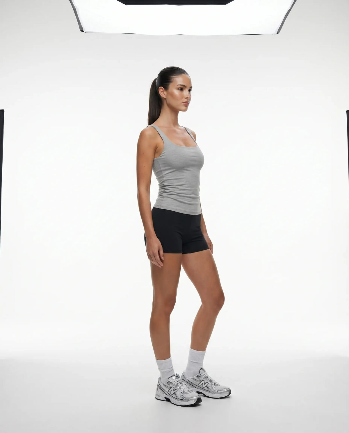 Lifestyle shot of woman wearing gray sleeveless tank top mid-movement during a gym workout session.