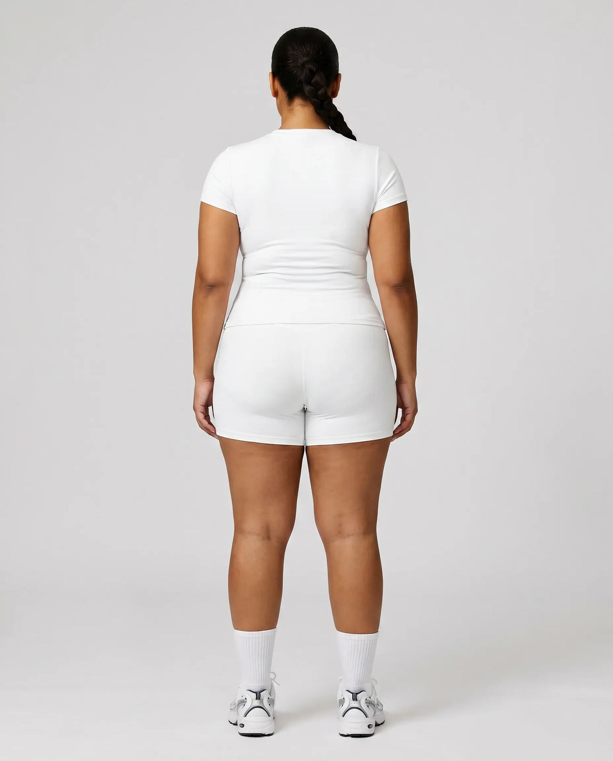 Female model from behind in studio showing the back fit of white ribbed crew neck tee.