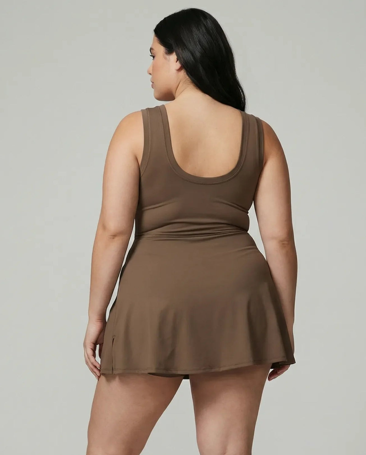 Model wearing brown active dress with wrap skirt detail, back studio view showcasing streamlined fit and minimal design.