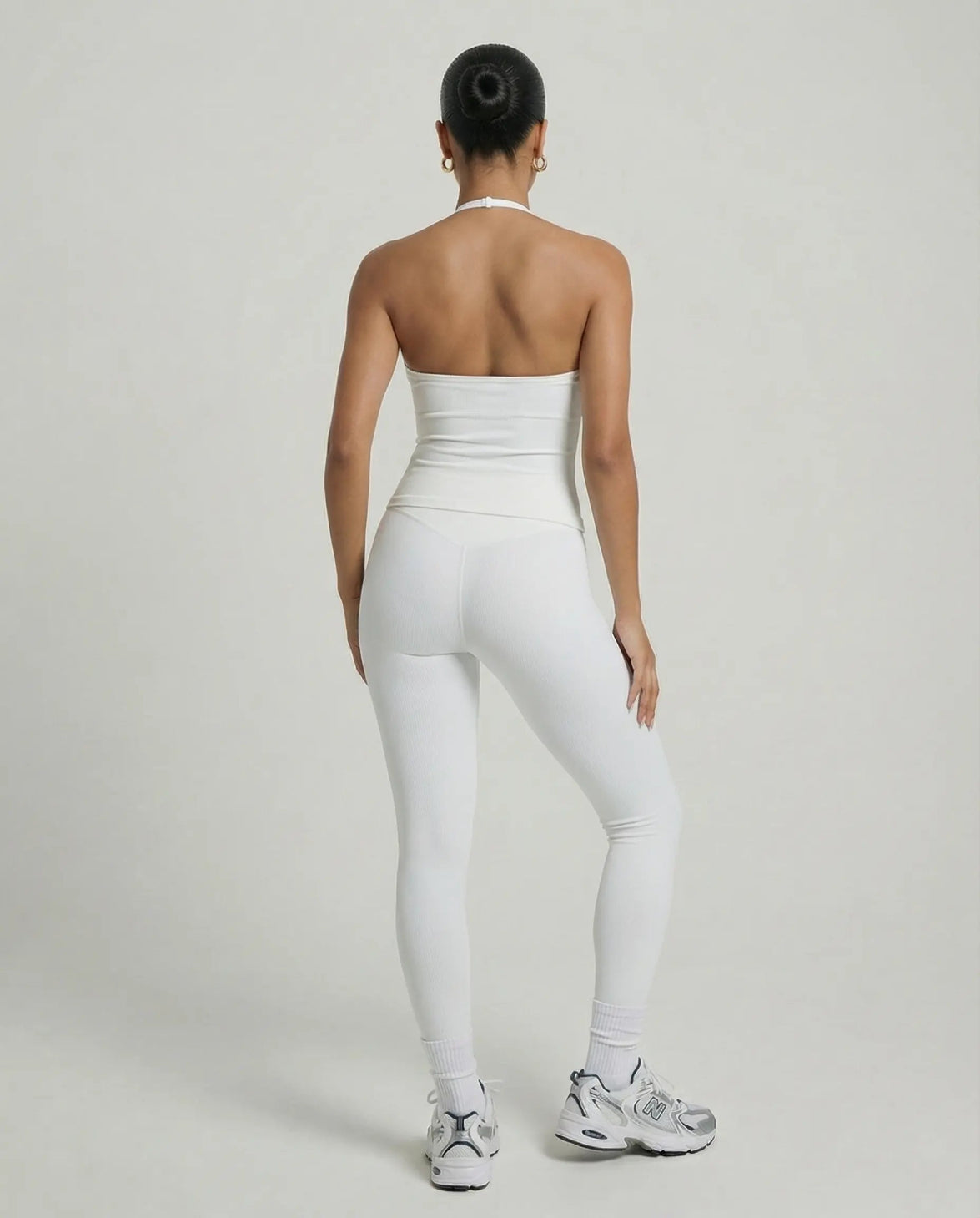 Model wearing a white seamless halter sculpt leggings set with high waist fitted leggings and athletic sneakers.