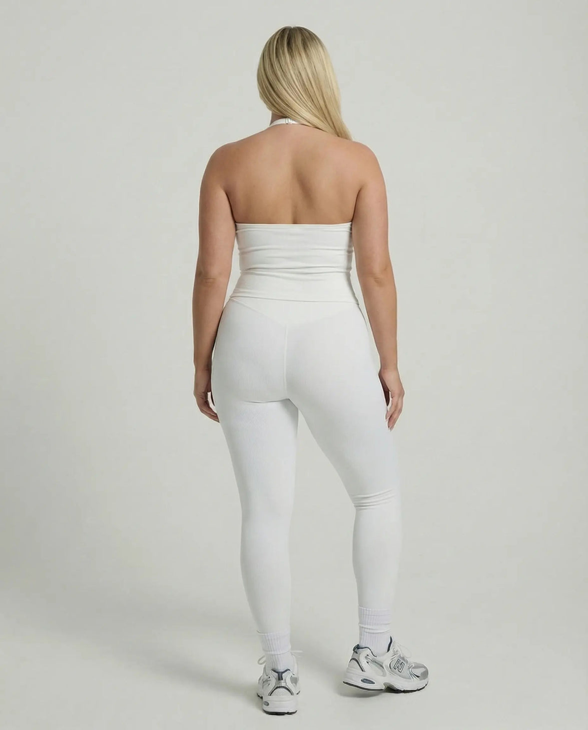 Model wearing a white seamless halter sculpt leggings set with high waist fitted leggings and athletic sneakers.