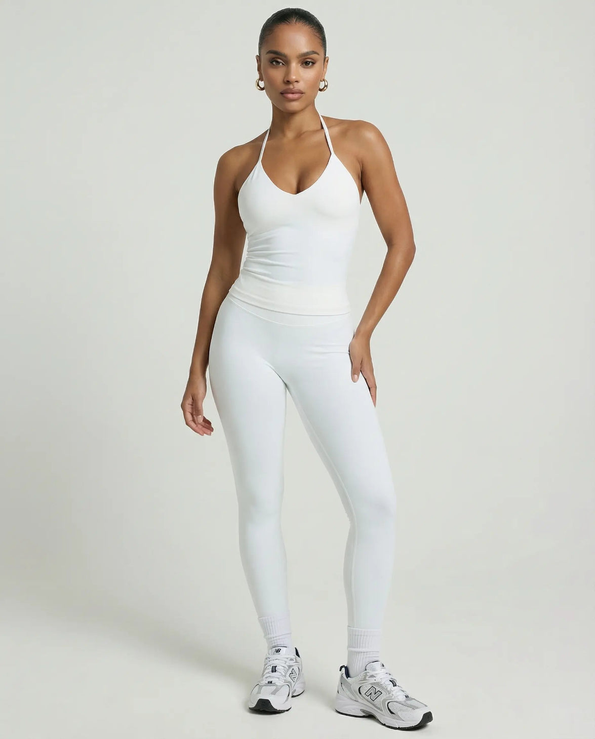 Model wearing a white seamless halter sculpt leggings set with high waist fitted leggings and athletic sneakers.