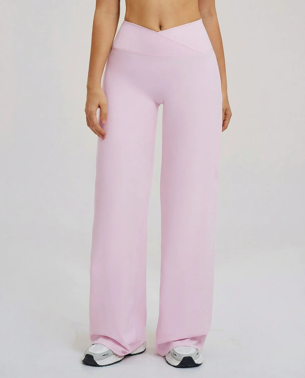 Close-up front view of pink high waist crossover wide leg leggings showing the sculpting V-panel waistband on model.