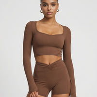 Seen women's activewear set with brown sculpting biker shorts and long sleeve top, front view showcasing fitted athletic design.