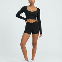 Black women's activewear set with sculpting biker shorts and long sleeve top, designed for workout comfort and support.
