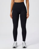 Front view of seamless high waist sculpting compression leggings in black, showing ribbed waistband and full-length squat-proof fit paired with white sneakers.