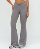 Front view of grey ruched high waist flare yoga leggings featuring a sculpting V-shaped waistband and flared leg silhouette, paired with grey sneakers.