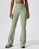 Woman wearing green flare high waist sculpting yoga leggings with a matching crop top and sneakers, front view showing the wide waistband and full-length flare silhouette.