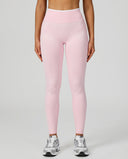 Front view of seamless high waist sculpting compression leggings in pink, showing smooth no-front-seam silhouette paired with silver New Balance sneakers.