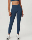 Front view of seamless high waist sculpting compression leggings in blue, showing full-length silhouette with ribbed waistband and second-skin fit paired with white sneakers.