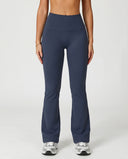 Front view of flare high waist sculpt yoga leggings in navy featuring a wide compression waistband and full-length flare leg silhouette paired with white sneakers.