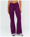 Front view of ruched high waist flare yoga leggings in purple featuring a sculpting V-shaped waistband and flowing flare leg silhouette, paired with grey sneakers.