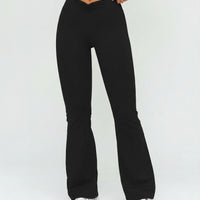 Front view of black high waist flare leggings featuring a ruched V-shaped crossover waistband and wide flare leg, paired with sneakers.