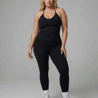 Model wearing a black seamless halter sculpt leggings set with high waist fitted leggings and athletic sneakers.