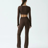 Woman wearing a fitted long sleeve crop top and high waist flare leggings activewear set styled with athletic sneakers.