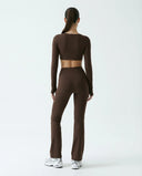 Woman wearing a fitted long sleeve crop top and high waist flare leggings activewear set styled with athletic sneakers.