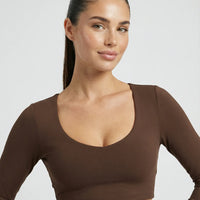 Woman wearing a fitted long sleeve crop top and high waist flare leggings activewear set styled with athletic sneakers.