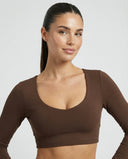 Woman wearing a fitted long sleeve crop top and high waist flare leggings activewear set styled with athletic sneakers.